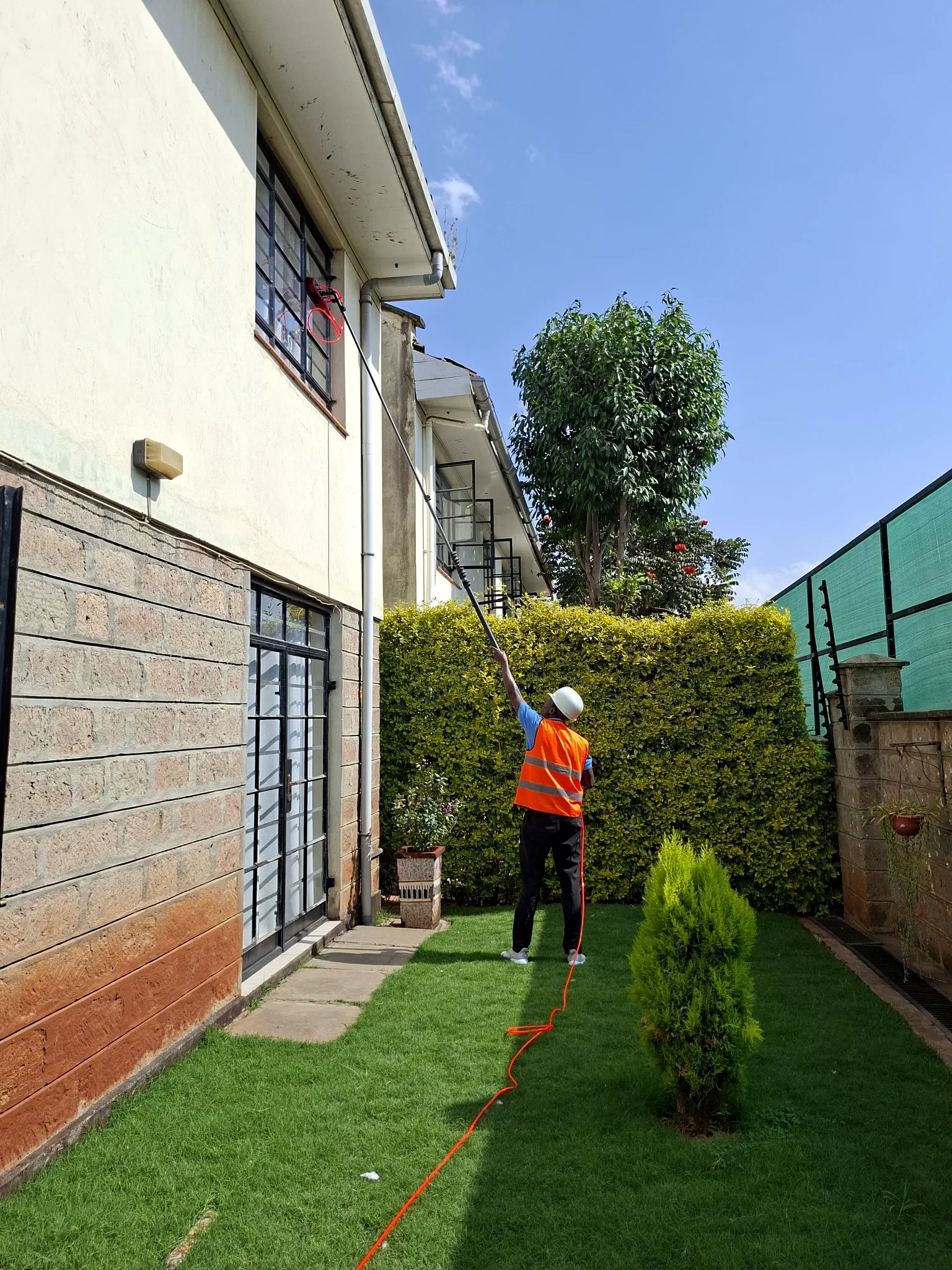 Dirty Nuvora technician cleaning upper-level residential windows in Kenya